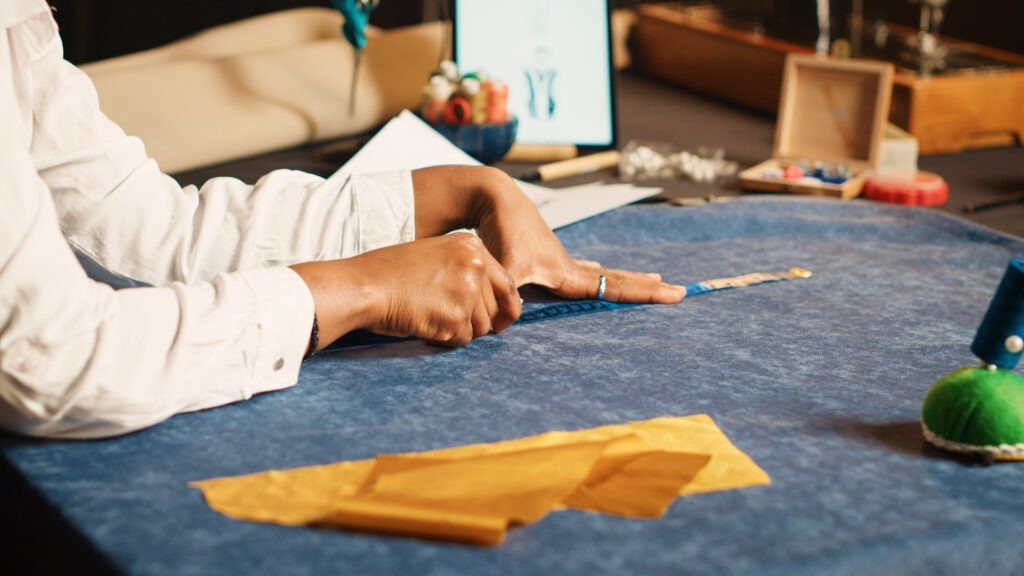 Young tailor using meter on fabric for custom made clothes collection, sewing industry. Female couturier doing measurements to make luxury design for clients. Handheld shot. Close up.